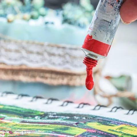 A drop of red paint is squeezed from a tube.