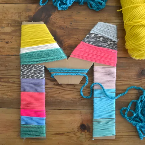 Image of a cardboard letter wrapped in yarn.