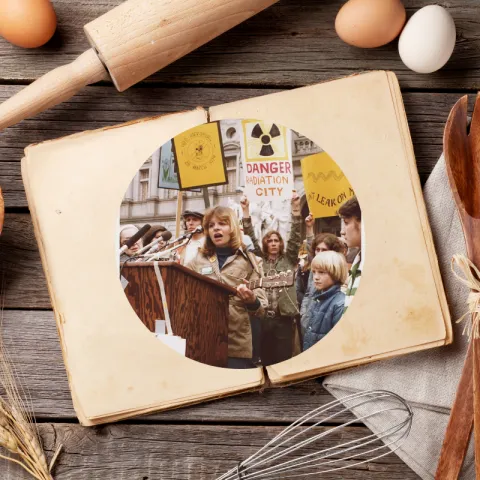 An open cookbook lays on a table. Inside, we see an image of nuclear protesters from the 1970s.