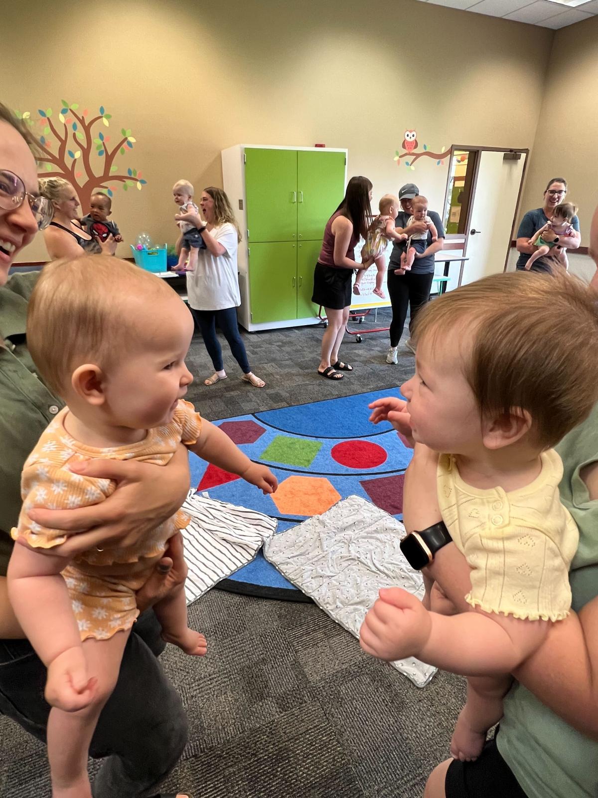 Image of two babies smiling at each other.