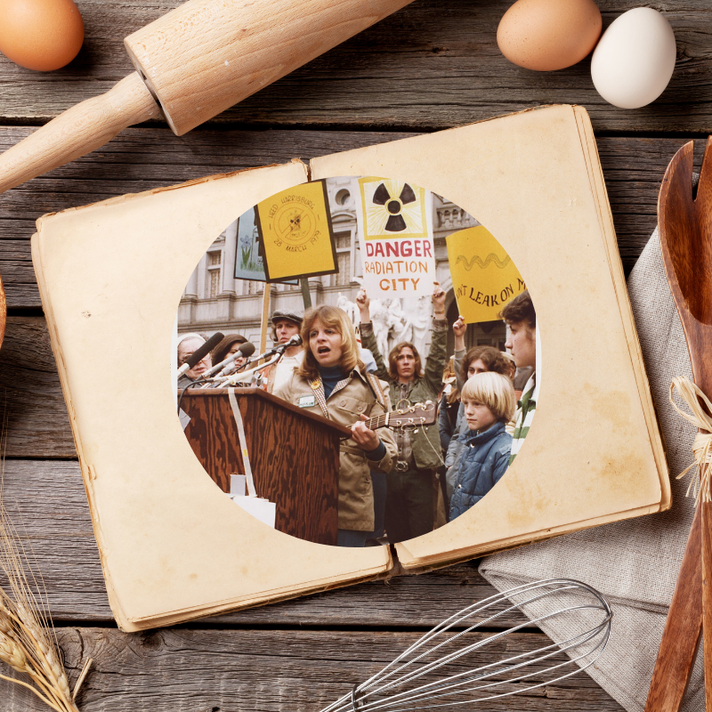 An open cookbook lays on a table. Inside, we see an image of nuclear protesters from the 1970s.